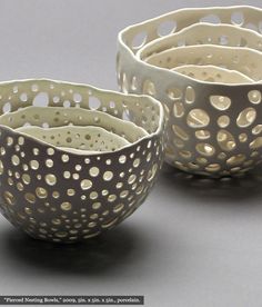 three white bowls with holes in them on a table