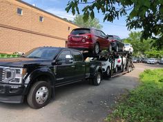 a black truck with two red cars on it's back