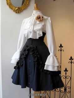 a dress with ruffles and a flower on the collar is displayed in front of a mirror