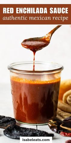 homemade red enchilada sauce in a glass jar with spoon and cookies on the side