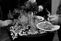 three people are sitting at a table with food and wine glasses in front of them