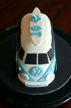 a cake shaped like a bus with a surfboard on the top is sitting on a black plate