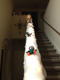 there are stuffed penguins on top of the white fluffy pole next to the stair case