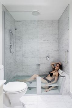 a woman laying in a bathtub next to a toilet