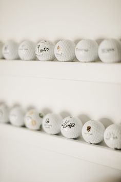 several white golf balls lined up on the shelf in front of each other with writing on them