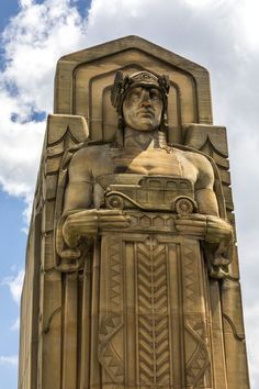 a tall building with a statue on the side and a blue sky in the background