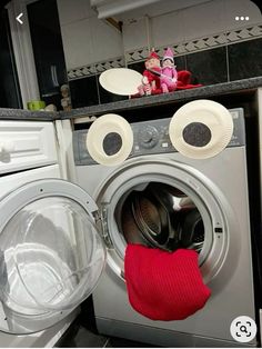 a washing machine with paper plates on the front, and a red mitt next to it