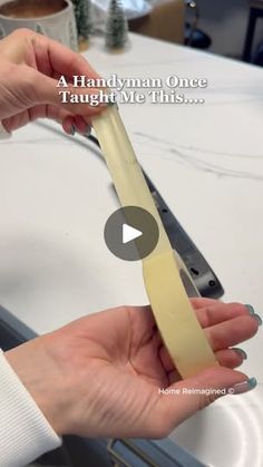 a woman is holding a piece of tape in her hand while standing next to a sink