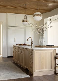 a large kitchen with an island in the middle and two pendant lights hanging from the ceiling