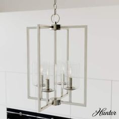 a chandelier hanging from the ceiling in a room with white tiles and black countertops