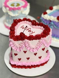 two heart shaped cakes sitting on top of white plates with red and pink icing