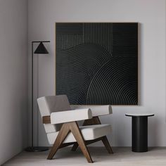 a white chair sitting in front of a black and white painting on the wall next to a table