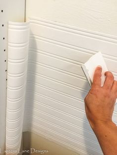 a person using a sponge to clean the wall in front of a white paneled door