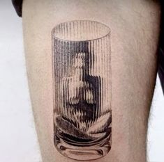 a man's leg with a tattoo on it and a glass filled with water