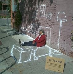 a man sitting on the side of a building next to a brick wall with graffiti