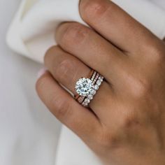 a woman's hand with a diamond ring on her finger and two wedding bands