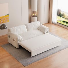 a white couch sitting on top of a hard wood floor next to a large window