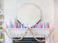 a fireplace decorated with pink, blue and white candles in front of a mirror on the mantle