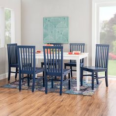 a dining room table with four chairs and a rug on the floor in front of it