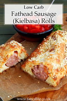 low carb fathead sausage kielbasa rolls on a cutting board with a bowl of tomatoes in the background