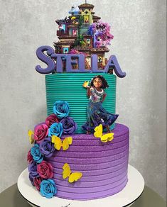 there is a colorful cake with the name stella on it and flowers in front of it