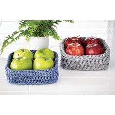 two baskets filled with apples sitting on top of a white counter next to a potted plant