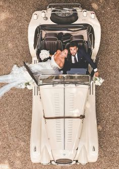 a bride and groom are sitting in the back of an old vw buggy