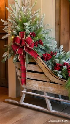 a sleigh decorated with evergreens, pine cones and red berries for christmas