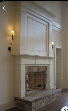 an empty room with a fireplace in the center and two lights on either side of it