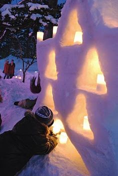 people are gathered around an igloose in the snow at night with lit candles