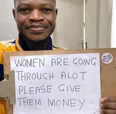 a man holding a sign that says women are going through alot please give them money