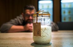 a man sitting at a table in front of a glass jar with food on it