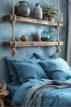 a bed with blue linens and pillows in a room that has two shelves on the wall