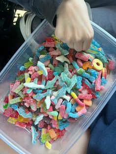 a person holding a plastic container filled with colorful candies in it's hands