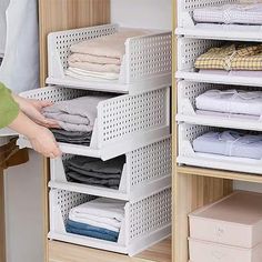 a person standing in front of a closet filled with folded shirts and other clothing items