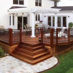 a wooden deck with steps leading up to the front door and covered patio area next to it