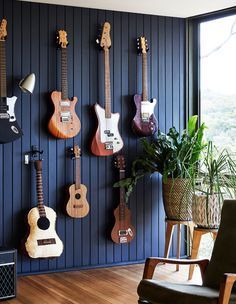 several guitars are hanging on the wall next to a potted plant