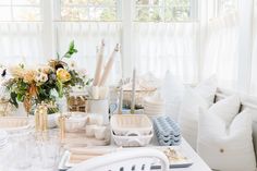 the table is set with white dishes and flowers in vases, plates, cups, utensils and napkins