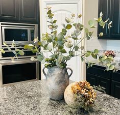 two vases filled with flowers sitting on top of a kitchen counter next to an oven