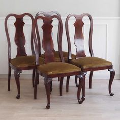 four wooden chairs sitting next to each other on top of a hard wood floor