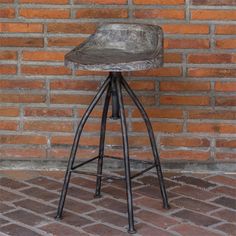 an old wooden stool sitting in front of a brick wall with metal barstools