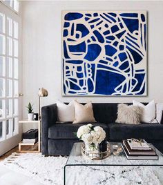 a living room with a couch, coffee table and large painting on the wall above it