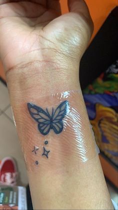 a hand with a butterfly tattoo on it's left wrist and stars around the wrist