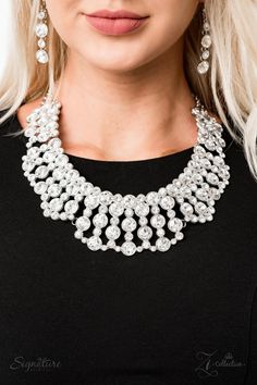 a woman wearing a black top and silver necklace with white stones on the collarline