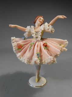 a figurine of a woman in a pink dress with flowers on her skirt