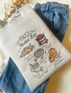 a pair of jeans and a t - shirt with embroidered designs on them sitting next to each other