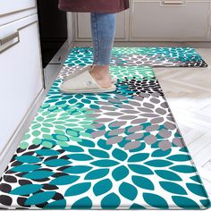 a woman standing on top of a kitchen floor next to a rug with blue and green flowers