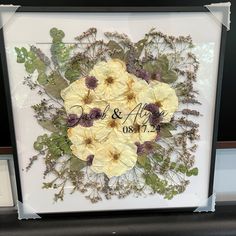 a white frame with yellow and purple flowers in the center is on display at a store