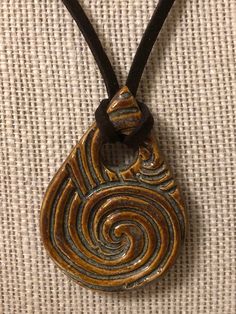 "this beautiful swirly designed teardrop pendant is on an 18\" brown suede necklace, but the fit will be tighter because the pendant is wrapped." Clay Necklace Pendant Aesthetic, Adjustable Brown Teardrop Jewelry, Unique Brown Spiral Jewelry, Unique Brown Teardrop Necklace, Brown Spiral Necklace For Gifts, Unique Brown Teardrop Pendant Jewelry, Brown Spiral Jewelry As A Gift, Adjustable Brown Teardrop Necklace, Brown Teardrop Necklace For Gift