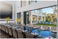 a dining room table set up with place settings and plates on it, in front of a large window